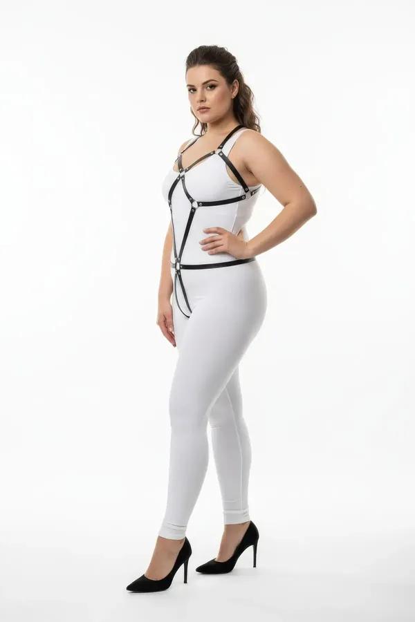 black faux leather full body harness with silver O-ring hardware and geometric chest strap frame worn over white outfit