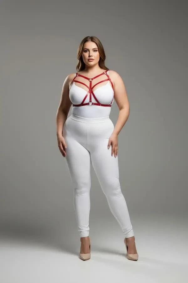 Strappy red faux leather body harness with silver O-ring worn over white bodysuit, plus-size model