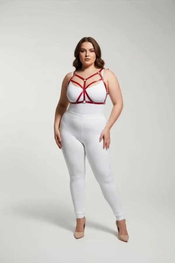 Strappy red faux leather body harness with silver O-ring worn over white bodysuit, plus-size model