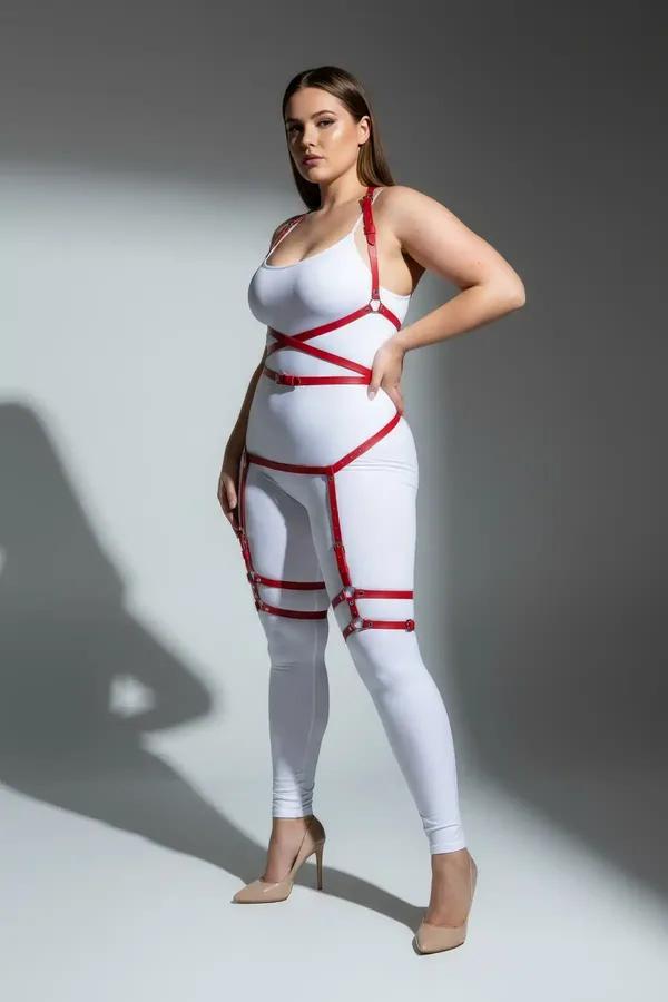 red faux leather full body harness with thigh straps and silver buckles worn over white bodysuit