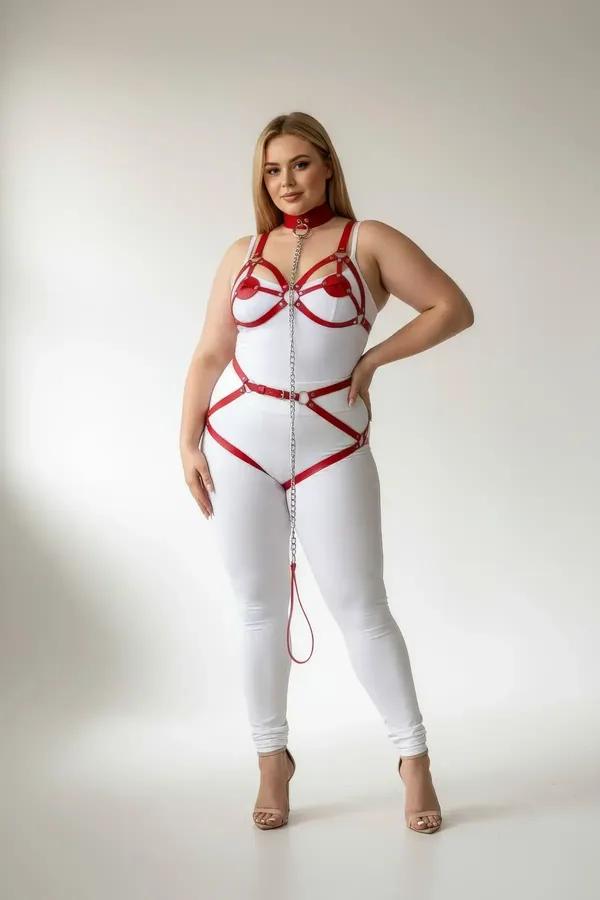 red faux leather body harness with silver chain detail and garter straps worn over white bodysuit, plus-size model