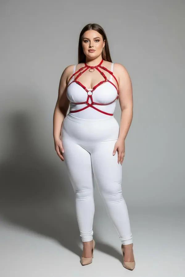 red faux leather cage harness bra with gold O-rings worn over white bodysuit plus size model