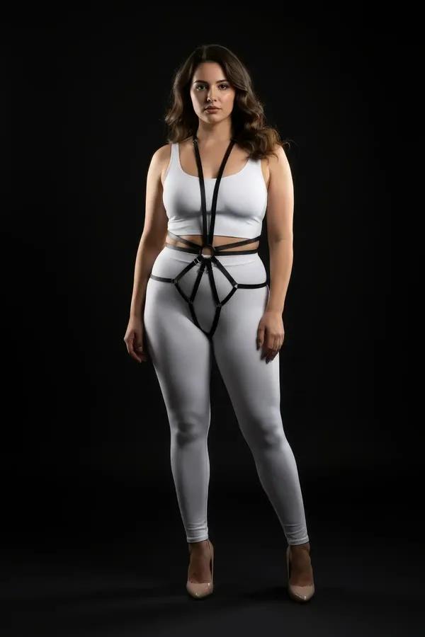 Black faux leather full body harness with starburst O-ring center worn over white bodysuit, silver-tone hardware, slim 1 cm s