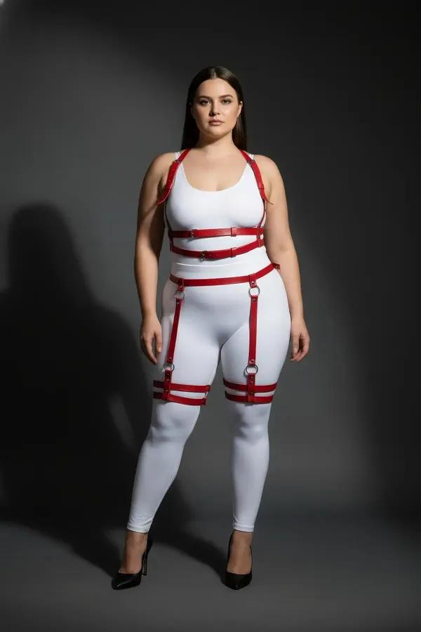 Red faux leather full body harness with dual thigh straps and silver O-ring buckles worn over white base layers