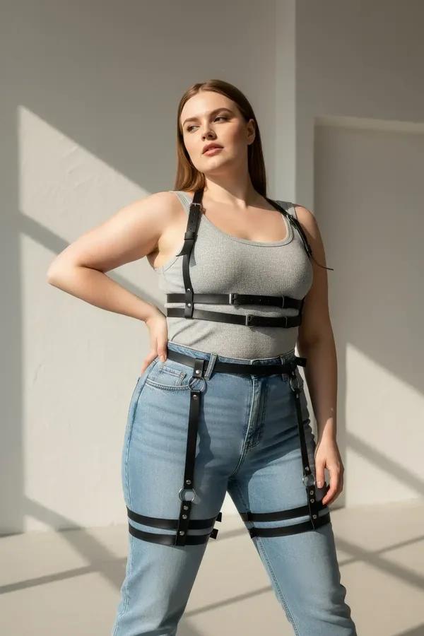 black faux leather body harness with garter straps worn over grey tank and jeans, double thigh bands and chest cage visible