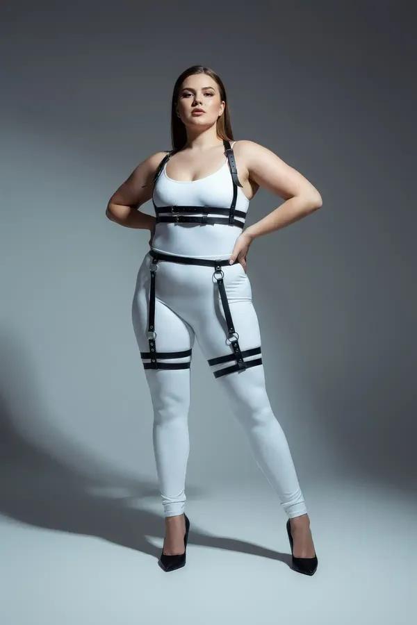black faux leather body harness with garter straps worn over grey tank and jeans, double thigh bands and chest cage visible