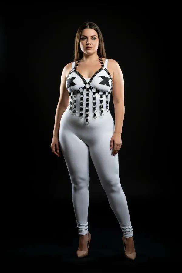 White strappy chest harness with cascading black faux leather straps and silver O-ring accents worn over white leggings