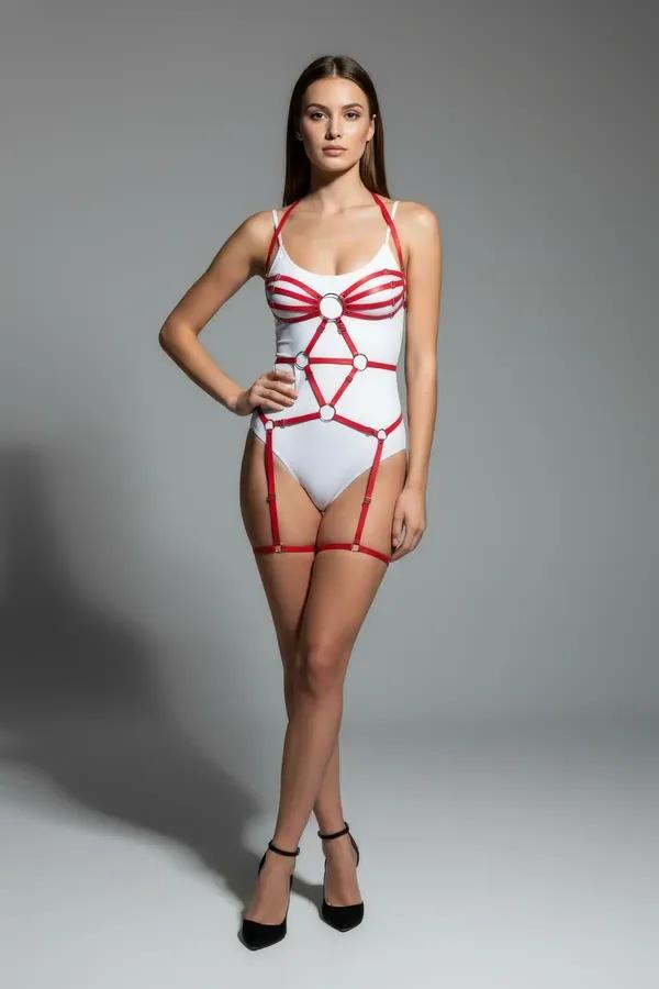 red faux leather strappy body harness with chest cage O-rings and matching thigh garters worn over white bodysuit