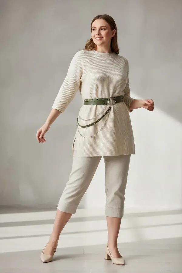 khaki faux leather waist harness with silver grommets O-ring and draped chain detail worn over cream knitwear