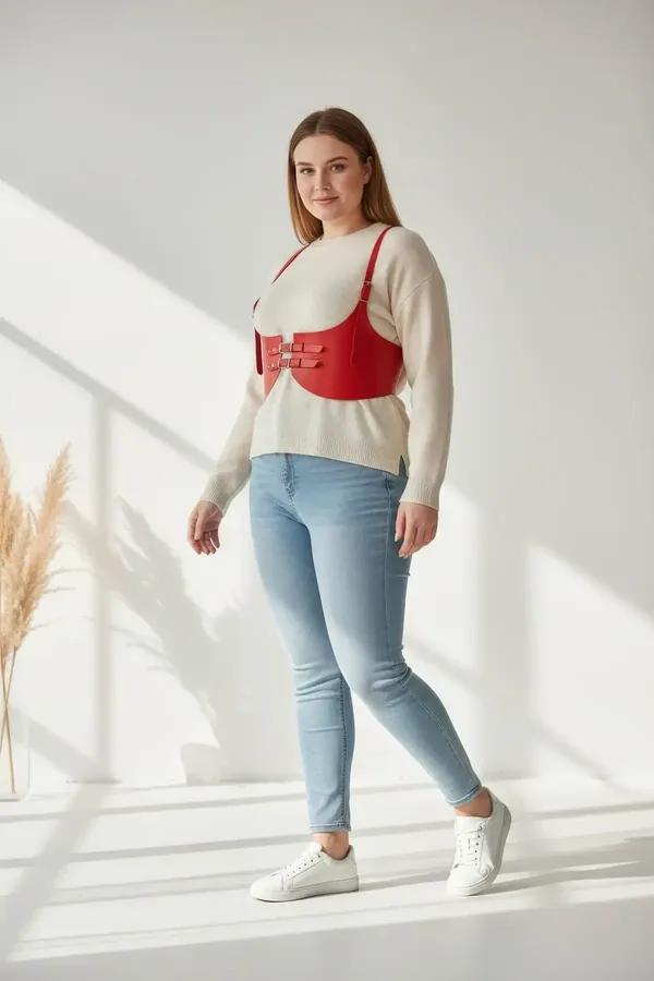 red faux leather underbust waist harness with dual silver buckles worn over cream knit sweater