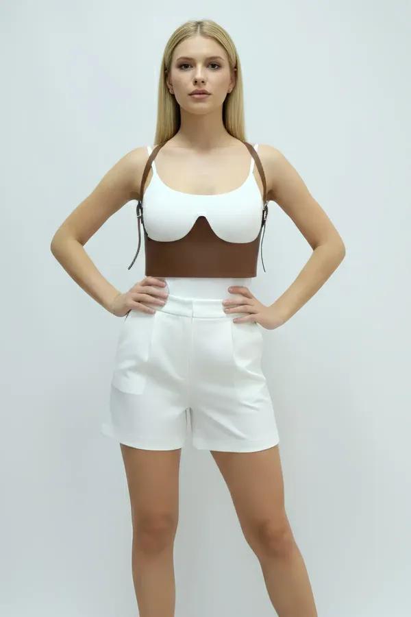 Brown faux leather underbust harness with sculpted bust cups and adjustable gold-buckle shoulder straps worn over white ribbe