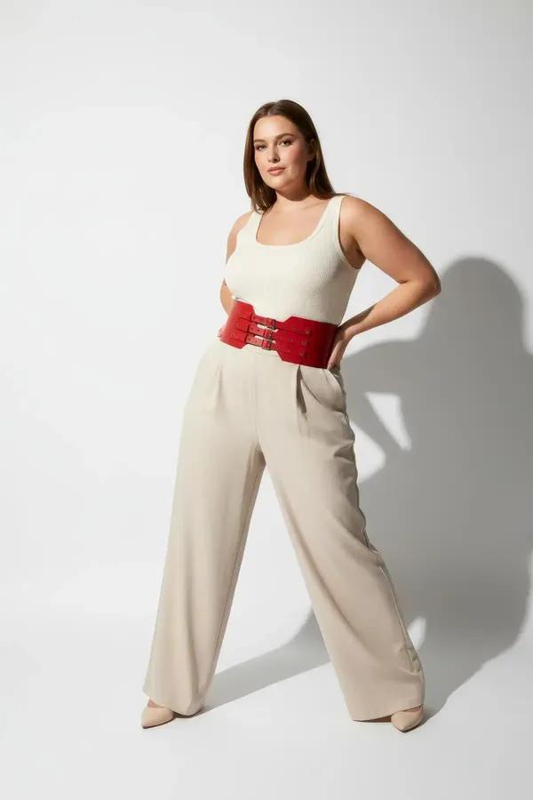 red faux leather wide corset waist harness belt with gold double buckles and decorative metal studs worn over cream top and p