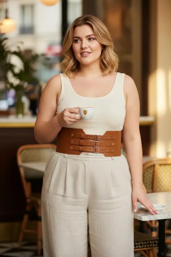 tan faux leather corset waist harness with three stacked silver buckles worn over cream tank and linen trousers