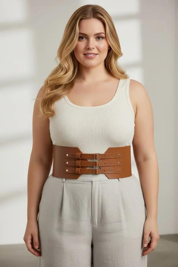 tan faux leather corset waist harness with three stacked silver buckles worn over cream tank and linen trousers