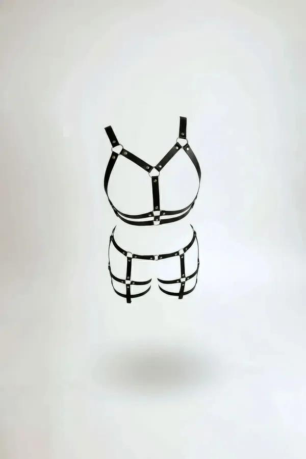 black faux leather O-ring harness bra and cage shorts two-piece set with silver stud hardware on white background