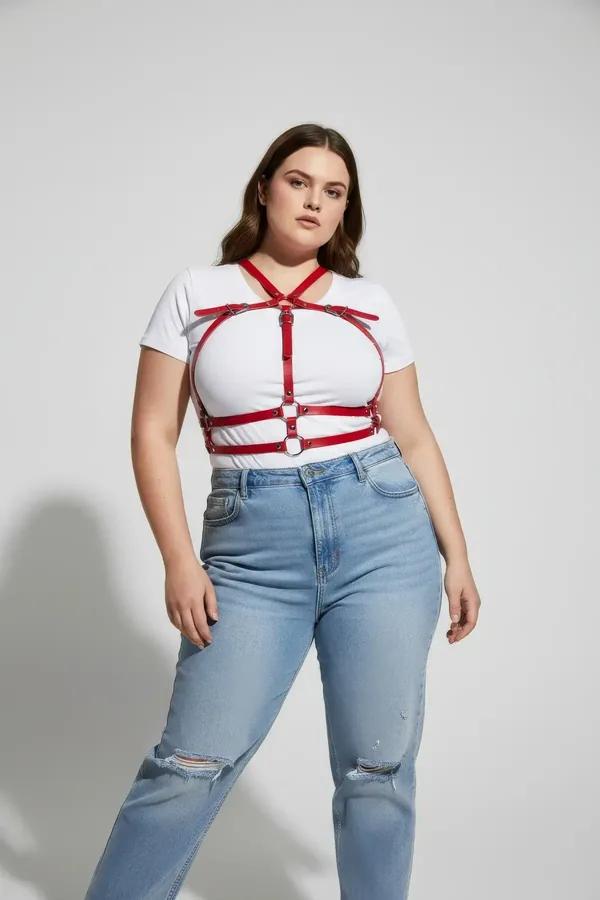 red faux leather caged chest harness with gold O-rings worn over white tank top, adjustable straps, front view