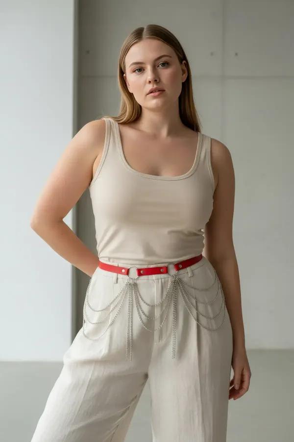 red faux leather waist belt with layered silver draping chains worn at natural waist over beige trousers