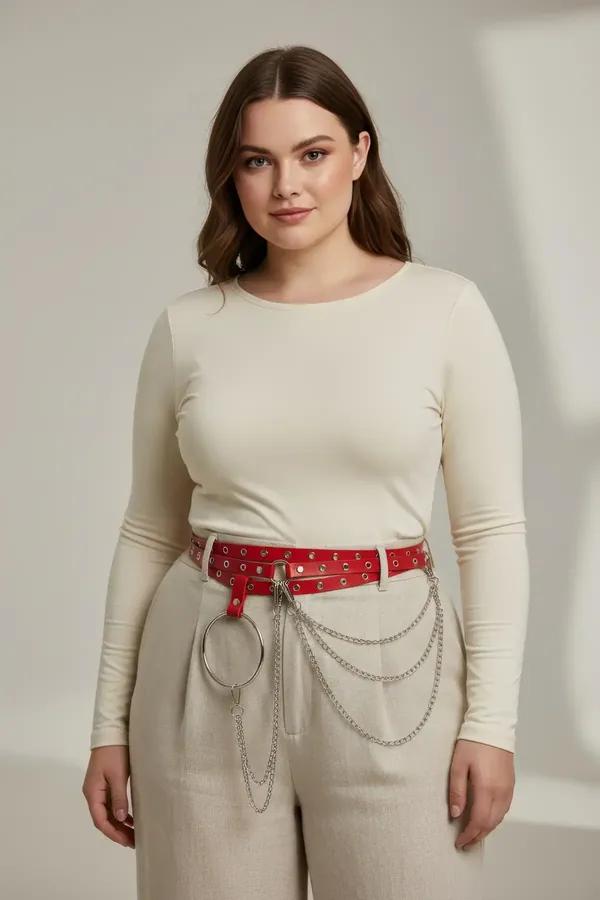 red faux leather belt with large silver O-ring and draped chain detail worn at natural waist over cream trousers