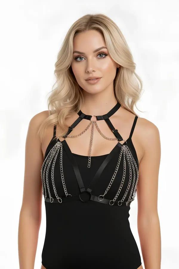 Black faux leather chest harness with cascading silver chain rows and O-ring hardware worn over red bodysuit