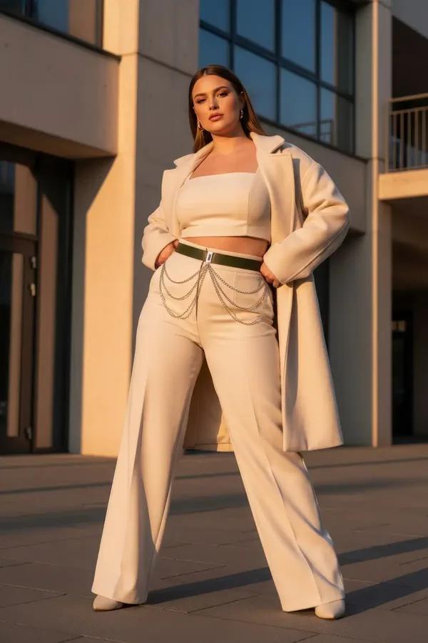 olive green faux leather waist belt with three-tier cascading silver chains worn over cream high-waisted trousers
