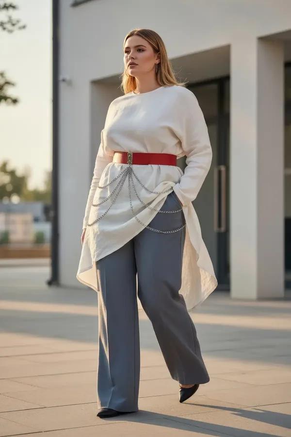 red faux leather wide waist belt with draped silver chains worn over white blouse and grey trousers