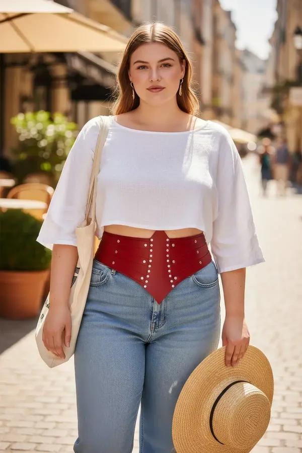 red faux leather waist harness corset belt with silver dome studs and pointed V-front panel worn over white crop top