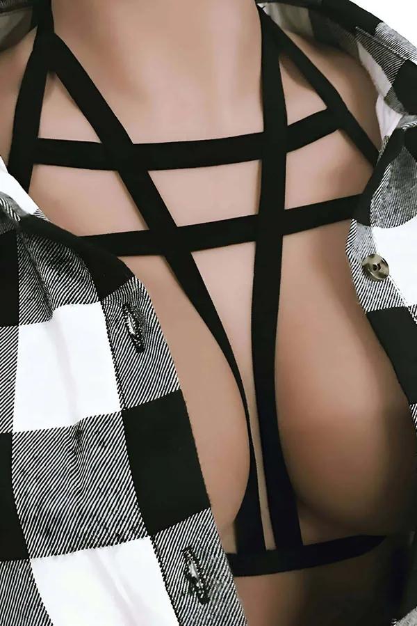 Black geometric chest harness with angular crossing elastic straps layered over plaid shirt, front view