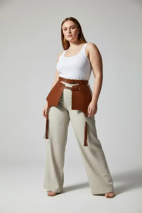 Tan faux leather waist harness with wide hip panels, dual silver buckle straps, and dangling tassels worn over white tank top