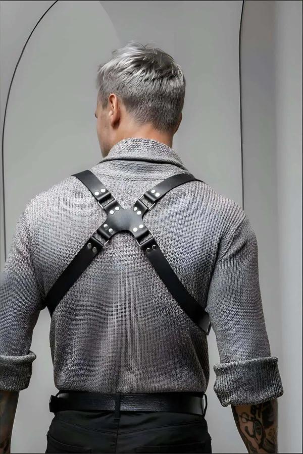 Erkek siyah vegan deri harness kemer gri kazak üzerine giyilmiş çapraz göğüs şeridi ve metal toka detayı