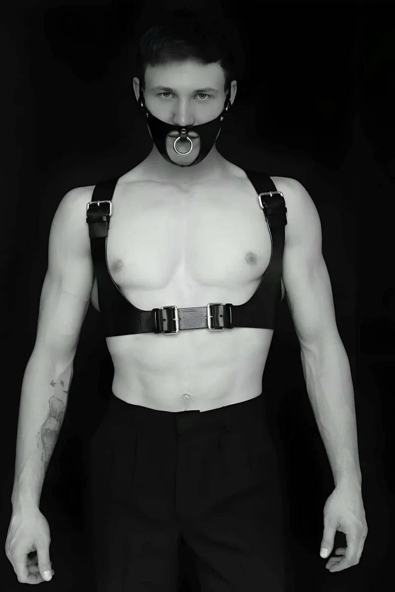 Black faux leather full body harness with detachable O-ring gag mask, silver buckle details.