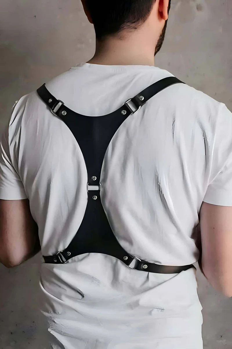 Black faux leather chest harness with buckles worn over white t-shirt