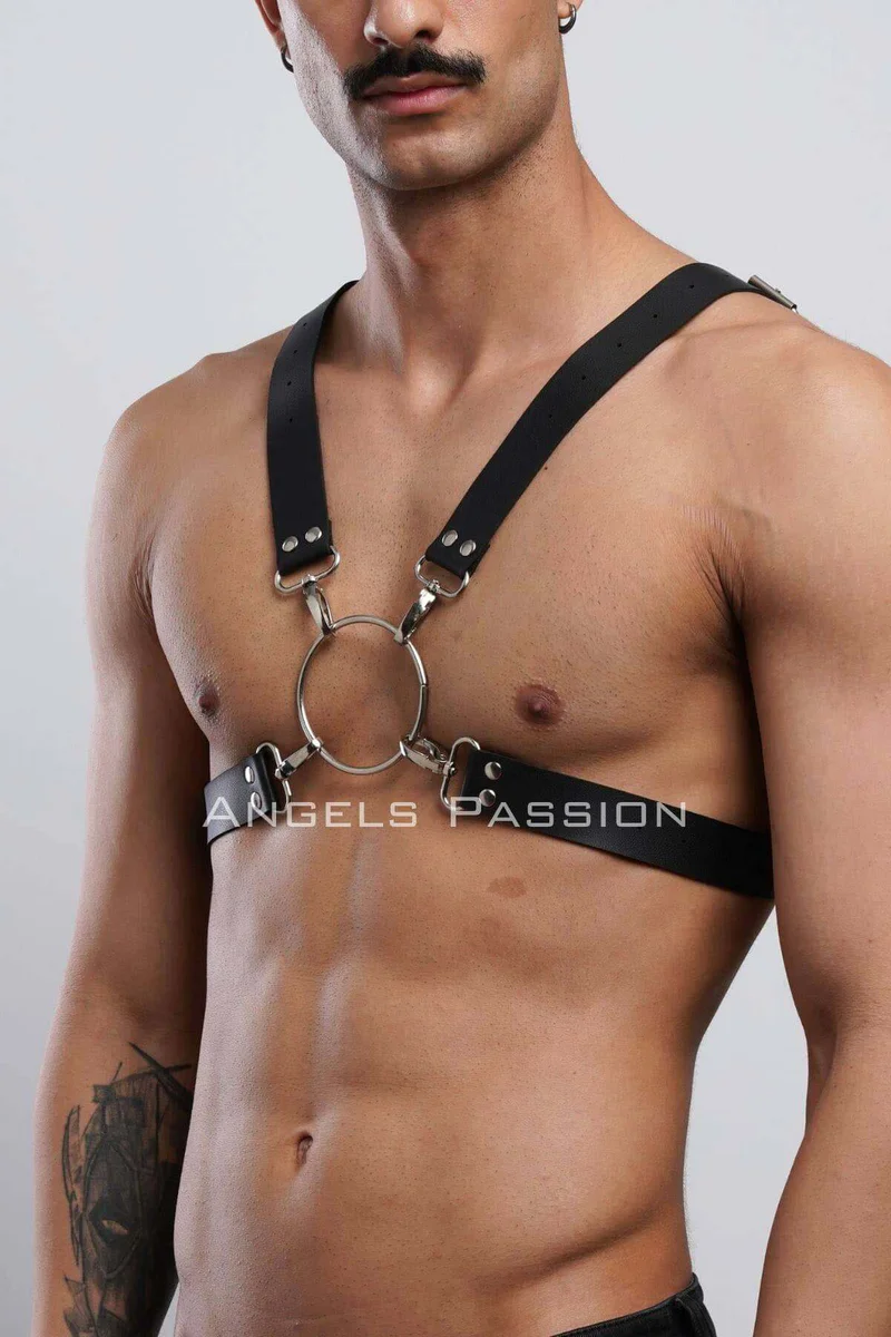 Black faux leather harness close-up with silver O-ring and X-back straps visible