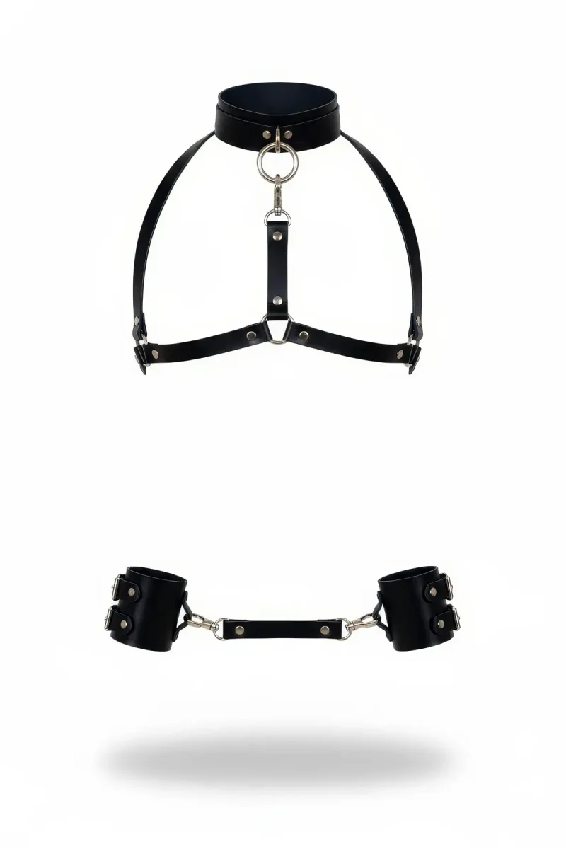 Black vegan leather body harness with adjustable straps and central O-ring, paired with detachable wrist cuffs.